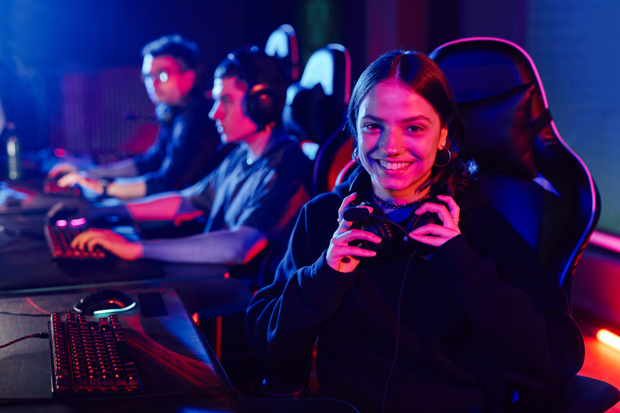 drie gamers op een rij, vrouwelijke gamer kijkt in de camera