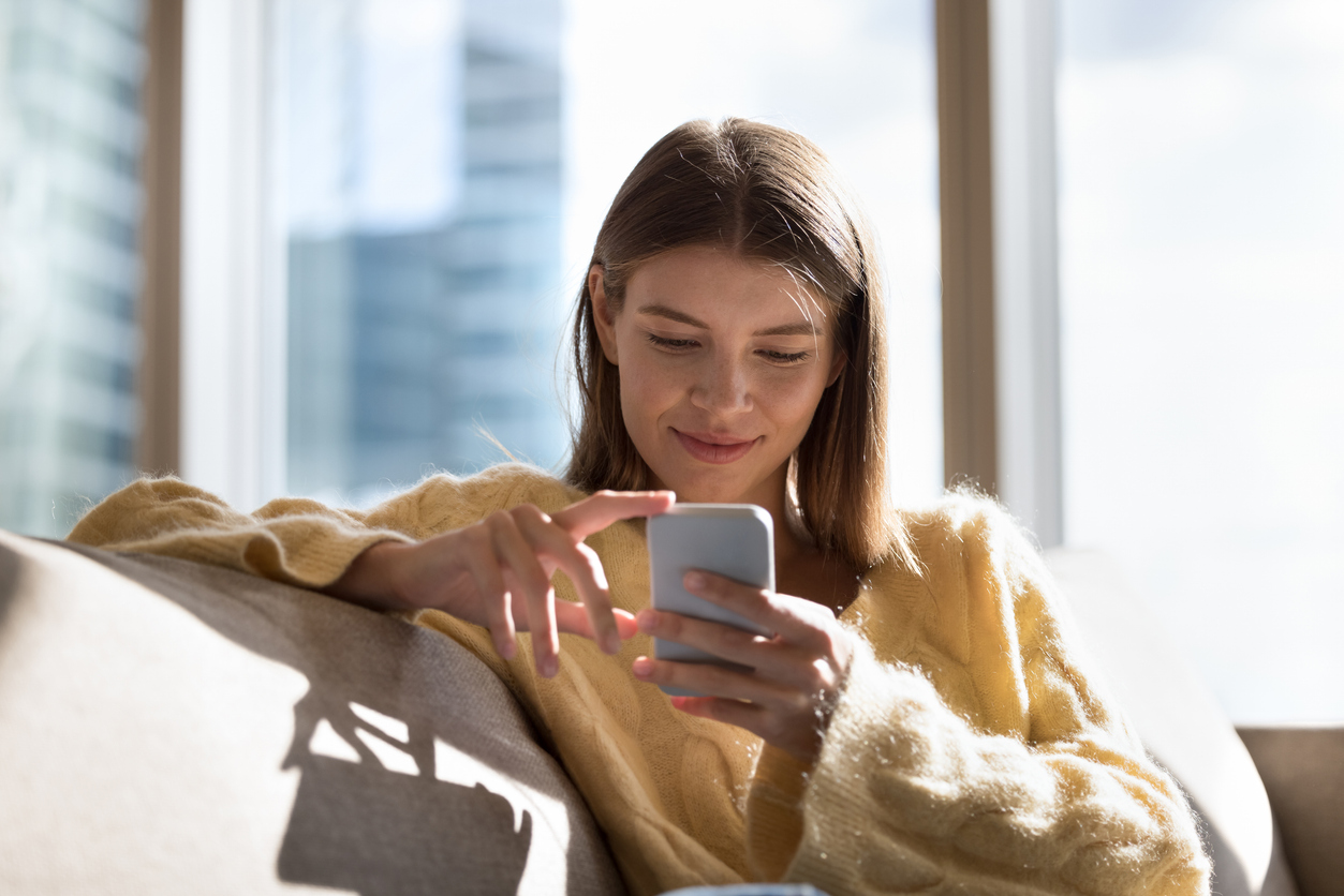 jonge vrouw die op de bank op telefoon zit